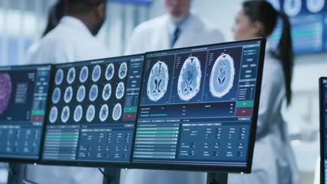 Computer-Screen-Showing-MRI,-CT-Image-Scan-of-the-Brain.-In-the-Background-Meeting-of-the-Team-of--Medical-Scientists-in-the-Brain-Research-Laboratory.-Neurologists-/-Neuroscientists-Having-Analytical-Discussion.