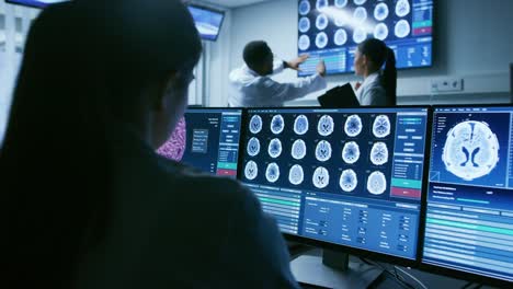 Über-der-Schulter-Schuss-der-weiblichen-Bilder-Mediziner-arbeiten-mit-Gehirn-Scan-auf-einem-Personal-Computer-im-Labor.-Neurologische-Forschungszentrum-arbeitet-an-der-Heilung-von-Hirntumoren.
