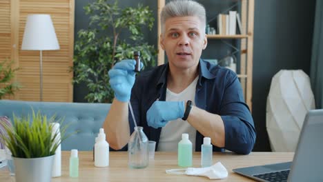 Portrait-of-handsome-guy-making-home-made-hand-sanitizer-in-apartment-talking-looking-at-camera