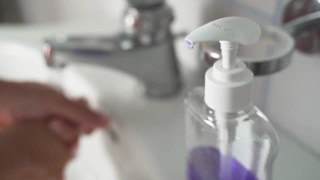 Young-Man-Using-Soap-Dispenser,-then-Washing-Hands-on-background
