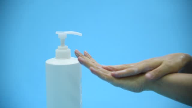 Mujer-manos-limpias-con-desinfectante-de-manos-sobre-fondo-azul