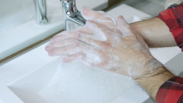 Hände-waschen-mit-der-richtigen-Ausrüstung-und-antibakterielle-Seife-auf-dem-Hintergrund-des-fließenden-Wassers-im-Bad.-Reiben-seine-Finger,-kratzen-seine-Hände.-Verhindern-Sie,-dass-schädliche-Mikroben-in-Ihre-Hände-gelangen