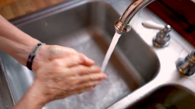 Frau-wäscht-ihre-Hände-in-einem-Edelstahlwaschbecken-in-Zeitlupe