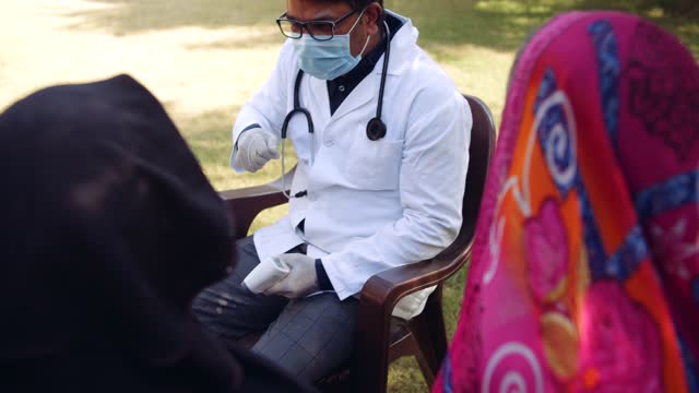 Ärzte-im-Freien-mit-einer-Seniorin-im-ländlichen-Indien
