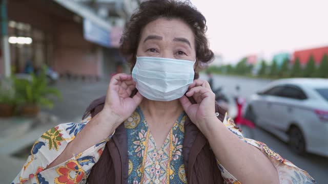 Asiática-Senior-señora-que-lleva-máscara-protectora-de-la-cara-de-pie-en-la-carretera-prevención-de-enfermedades-infecciosas-durante-el-virus-Corona-covid-19-distanciamiento-social,-riesgo-de-protección-contra-enfermedades,-espera-de-vacuna