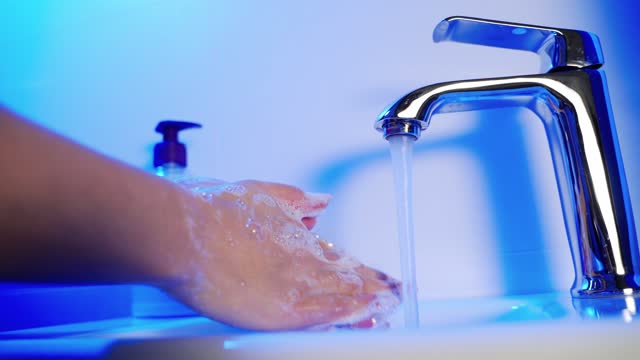 Woman-washing-hands-with-soap-over-sink-in-bathroom,-closeup