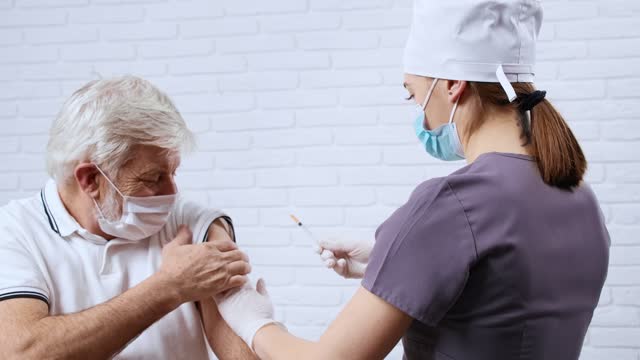Krankenschwester-in-Uniform-geben-Impfstoff-für-Patienten-in-Schutzmaske.