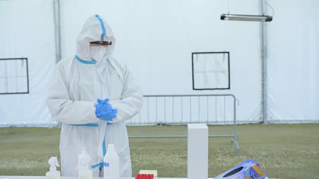 Man-in-protective-suit-with-mask-holding-sample-of-swab-after-a-drive-through-test-for-covid-19.-Infection-prevention-and-control-of-epidemic.