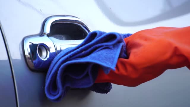 Hand-in-Glove-wiping-down-door-handle-surfaces-of-bronze-car-cleaning-covid-19-virus