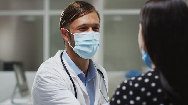 Kaukasischer-männlicher-Arzt-trägt-Gesichtsmaske-und-Handschuhe-unter-Tupfer-Test-vom-Patienten