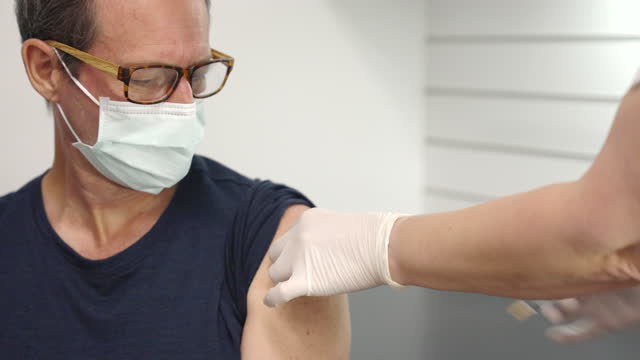 a-male-patient-watches-as-he-is-vaccinated-in-the-arm
