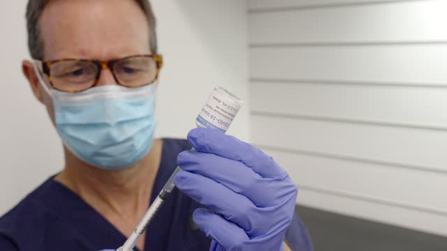 Mann-füllt-eine-Spritze-aus-einer-Coronavirus-Impfstoff-Durchstechflasche