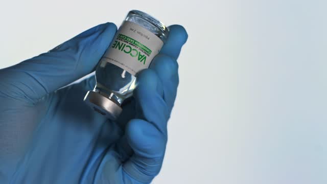 Doctor-in-medical-glove-holds-in-his-hand-a-vial-of-vaccine-for-injection-for-coronavirus-COVID-19-cure-in-research-laboratory.-Vaccination-concept,-pandemic.-Macro.-Bottle-flask.-SARS-Cov-2.-One-dose