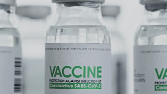 Geloopt.-Impfstoffkolben-für-die-CoVID-19-Coronavirus-Heilung-werden-im-Forschungslabor-langsam-rotiert.-Impfung,-Injektion,-klinische-Studie-während-der-Pandemie.-Flaschen,-Fläschchen-drehen-sich-im-Uhrzeigersinn.-Closeup-Makro