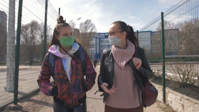 Mother-and-daughter-a-teenager-walking-down-the-street-in-protective-masks.