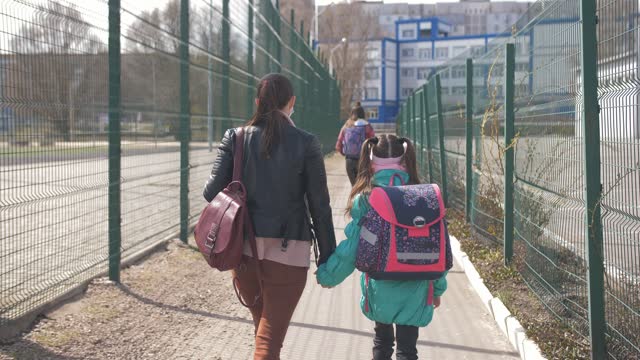 Mutter-und-Tochter-in-Schutzmasken-gehen-zur-Schule.