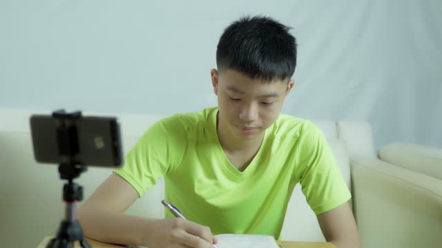 Un-adolescente-asiático-de-pelo-negro-está-estudiando-en-línea-en-casa-con-Smart-Phone