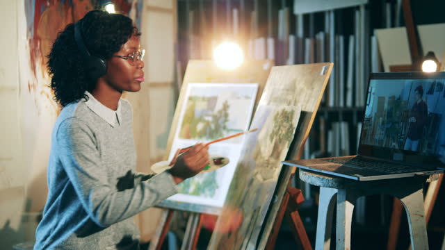 La-señora-africana-está-usando-un-tutorial-en-línea-para-pintar-una-imagen