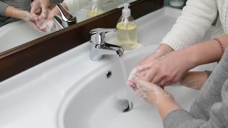 Mamá-ayudando-a-su-hijo-mientras-se-lava-las-manos