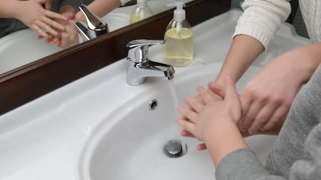 Mama-hilft-ihrem-Kind-beim-Händewaschen