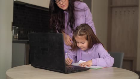 Schulmädchen-beschäftigt-mit-dem-Schreiben,-Blick-auf-Laptop-während-der-Heimschule-auf-Coronavirus---Kinder-E-Learning-Konzept,-virtuelles-Klassenzimmer-während-covid-19-Pandemie.