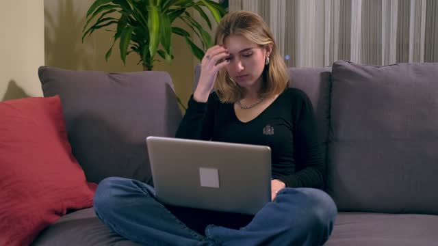 Joven-turca-usando-una-computadora-portátil-mientras-está-sentada-en-el-sofá.