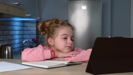 Kleine-Schülerin-hat-Online-Unterricht-auf-einem-Tablet,-während-sie-ihre-Hausaufgaben-hören,-um-die-Lehrerin