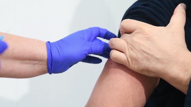 El-médico-inyecta-la-vacuna-contra-la-gripe,-la-neumonía-o-el-COVID-19-en-el-hombro-del-paciente