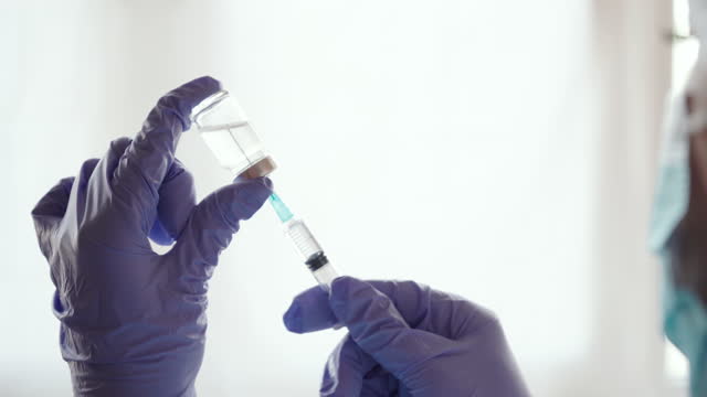 Un-médico-de-primer-plano-extrae-la-vacuna-de-la-botella-de-vidrio-a-la-jeringa,-vacunación,-4k