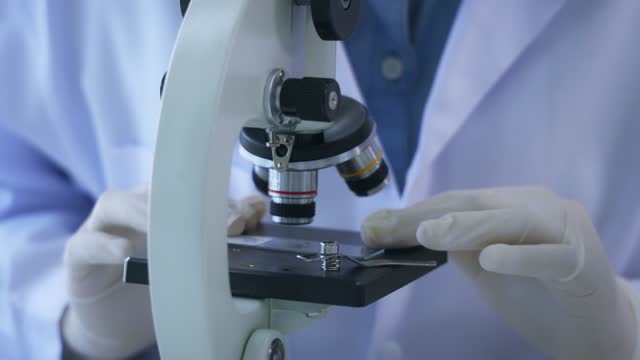 Woman-looking-through-microscope-in-lab
