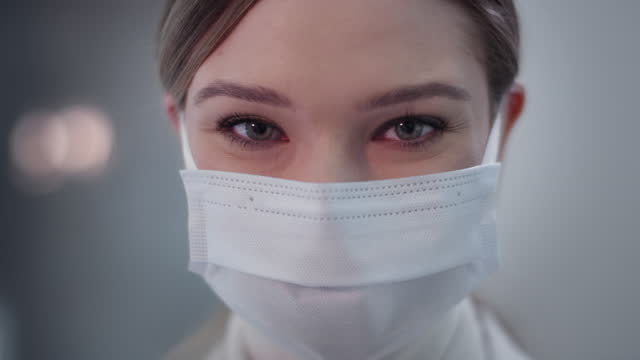 Ärztin-trägt-Maske-im-Labor.-Zufrieden-mit-ihrer-Arbeit.-Lächelnd-in-eine-Kamera