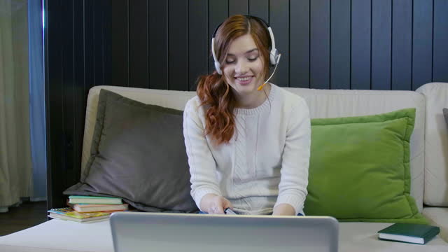 Young-Smiling-Student-Wearing-Headphones-Communicating-By-Video-Call-Doing-Distant-Chat-Working-From-Home.