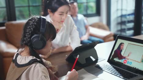 Homeschool-asiatische-kleine-junge-Mädchen-lernen-Online-Klasse-von-Lehrer-durch-digitale-Remote-Internet-Treffen-aufgrund-der-Coronavirus-Pandemie.-Kind-suchen-Computer-Laptop-Bildschirm-mit-Mutter-Unterstützung.
