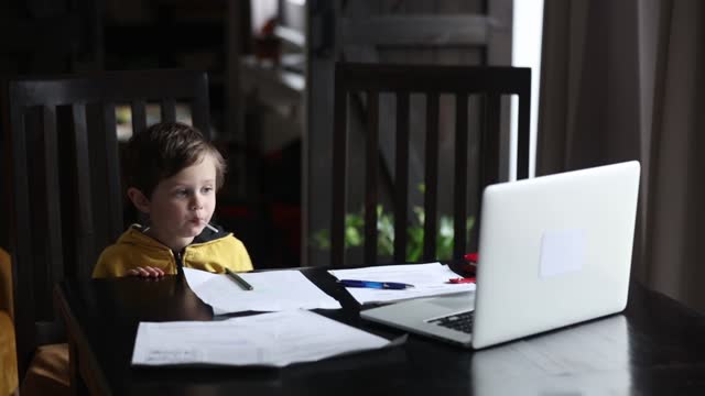 Niño-pequeño-se-alojó-en-la-mesa-con-computadora-portátil-y-documentos-para-la-lección-en-casa