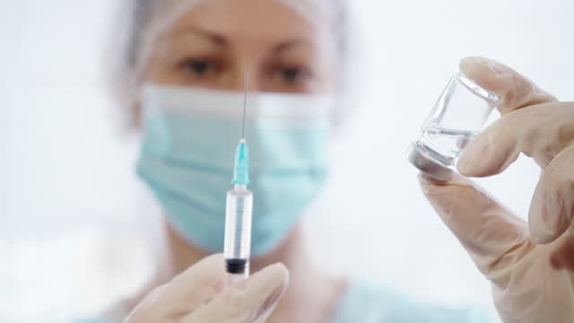 Weibliche-Ärztin-gießt-Medizin-in-Spritze-aus-Glasflasche