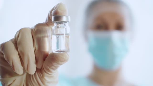 Mujer-doctora-en-uniforme-médico-sostiene-vacuna-vial-de-vidrio,-4k