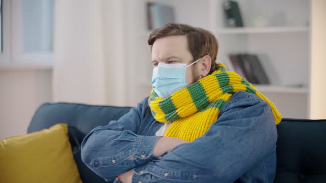 Young-man-coughing,-wearing-protective-mask-and-scarf,-social-distance,-covid-19