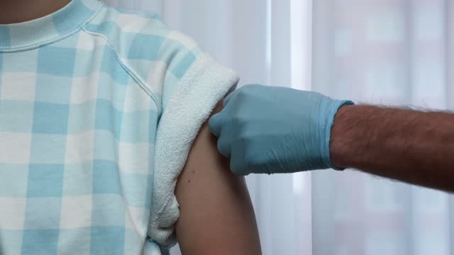Medical-healthcare-worker-in-blue-medical-safety-gloves-is-making-vaccine-injection-for-Covid-19-coronavirus-pandemic-to-patient-in-health-clinic.-Medical-syringe.-Healthcare-and-medical-concept