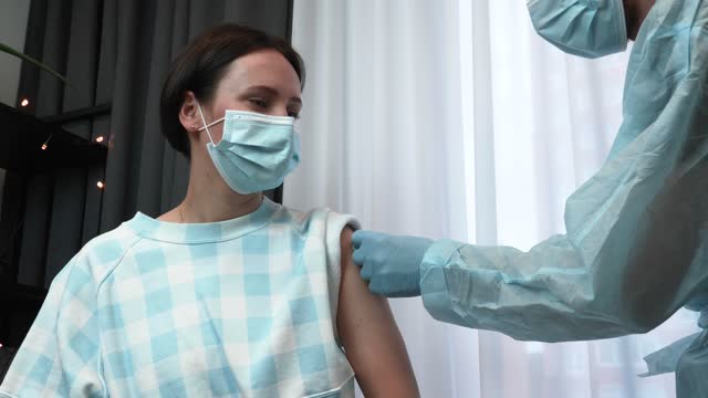 Young-woman-is-getting-coronavirus-covid-29-vaccination-from-doctor-at-clinic.-Vaccine-against-coronavirus.-Doctor-in-medical-gloves-holding-syringe-with-vaccine-of-2019-nCoV.-Vaccine-injection