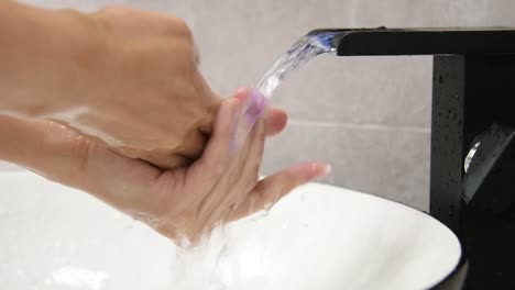 Vídeo-a-cámara-lenta-de-una-mujer-lavándose-las-manos-bajo-el-agua-corriente-en-el-baño