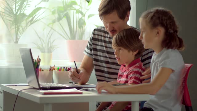 Fernunterricht-für-Kinder-zu-Hause.-Vater-erklärt-Tochter-und-Sohn-Schulmaterial-mit-einem-Laptop.