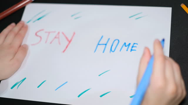 Child-boy-drawing-stay-home-slogan-on-a-paper-in-covid19-pandemic-disease,kids