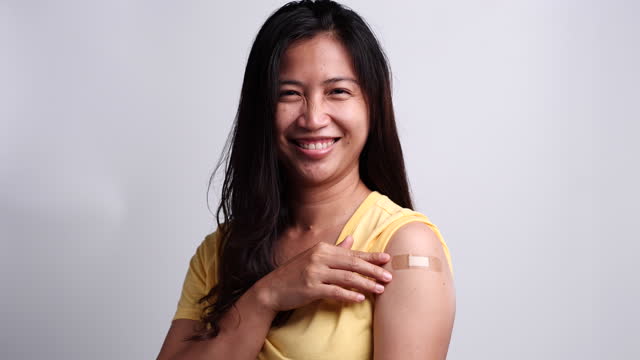 Frau-zeigt-ihren-Arm,-nachdem-sie-sich-geimpft-mit-dem-Gefühl-glücklich.-Konzept-der-Impfung,-geimpfte-Patienten,-Impf-Roll-out-Programm,-Coronavirus,-COVID-19.