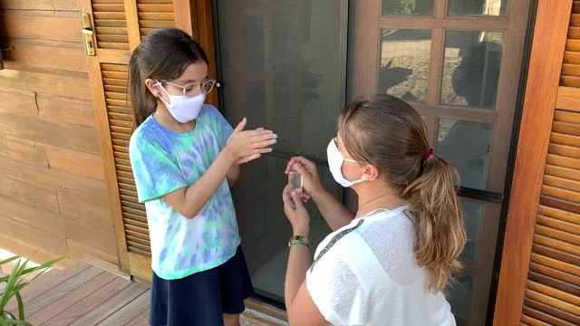 Little-girl-and-mother-getting-ready-fot-school-using-hand-sanitizer-and-protective-face-mask-during-Covid-19.