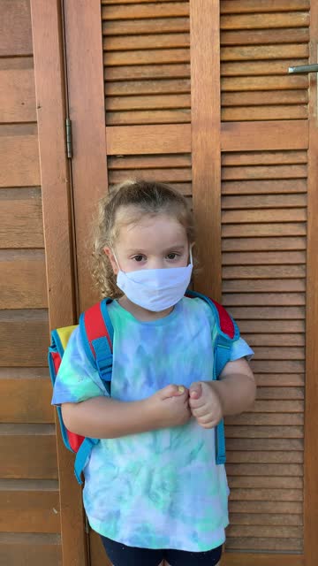 Little-girl-getting-ready-fot-school-using-hand-sanitizer-and-protective-face-mask-during-Covid-19.-Vertical-format-video