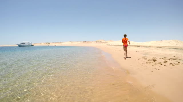 Mädchen-in-Badebekleidung-am-Meeresstrand-in-Wüste-weglaufen
