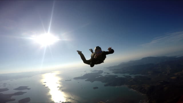 Skydiver-having-fun-above-the-sea-&-mountains-4K