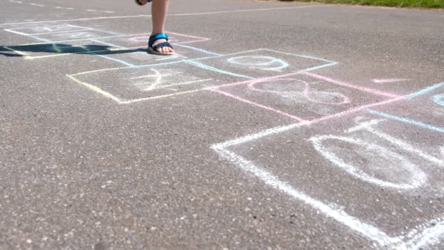 Boy-jumps-playing-hopscotch-in-the-street.-Close-up-legs.