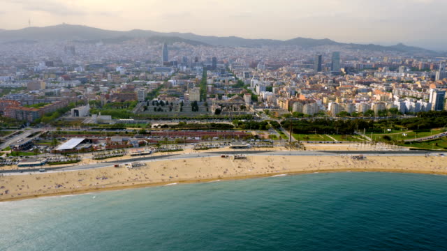 Flying-along-Barcelona-shore-with-city-skyline,-Spain