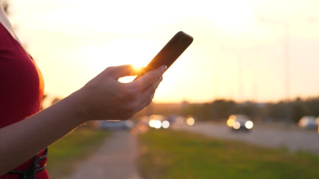 Frau-Hand-mit-Smartphone-gegen-die-Straße-mit-Autos-zu-fahren
